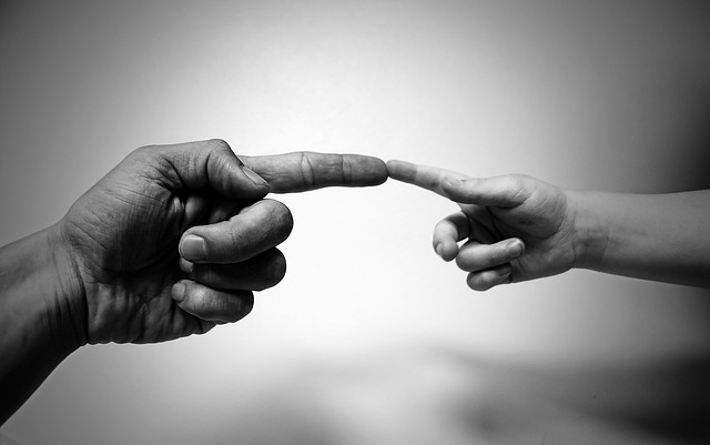 large hand, small hand, fingers touching, black and white